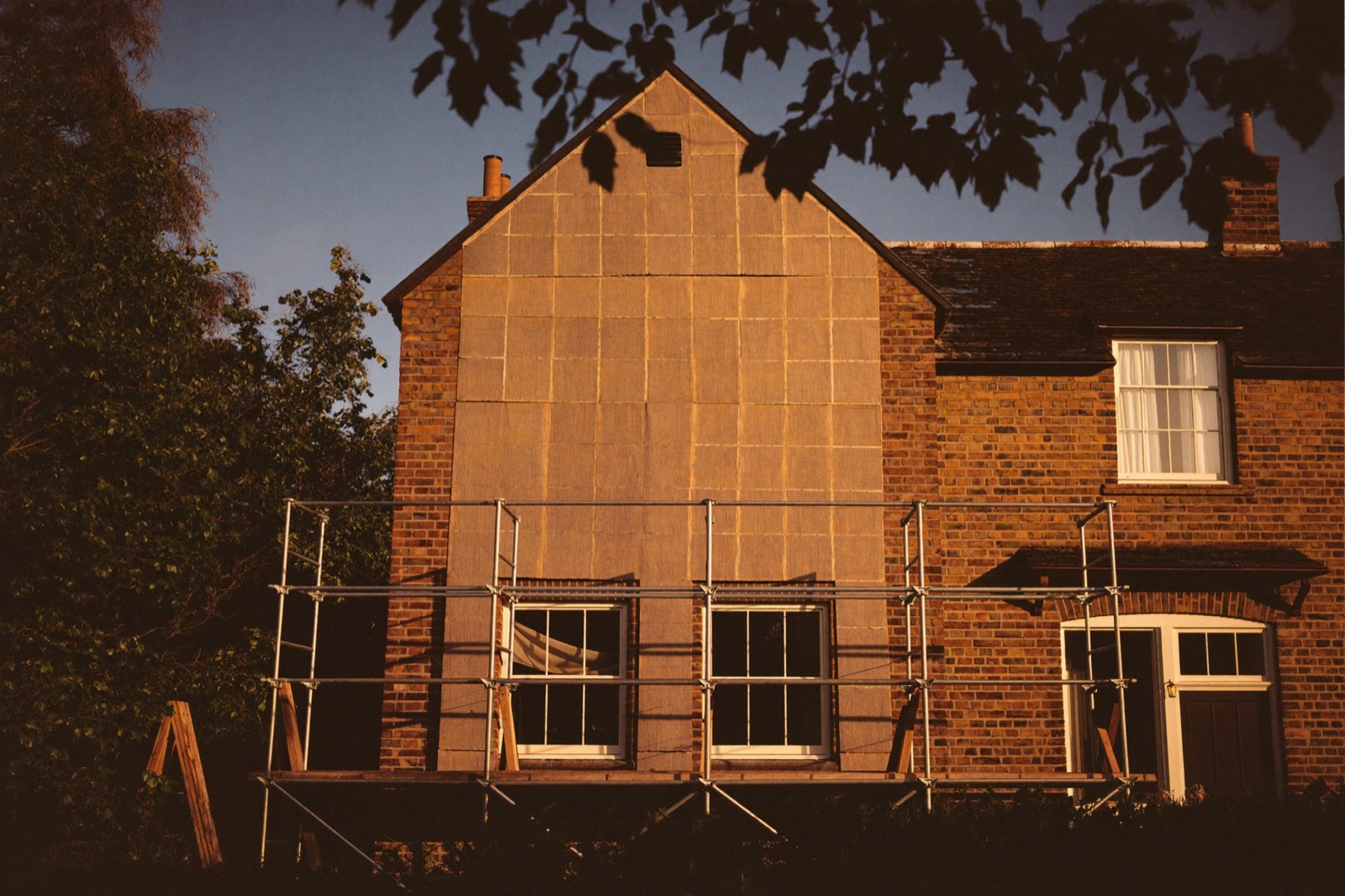 A period brick house under renovation, scaffolding on the facade.